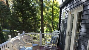 A wooden deck with wicker rocking chairs and a small table.