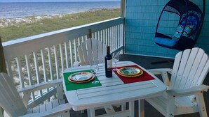 Een wit houten terras met een tafel gedekt voor twee personen, met uitzicht op een strand.