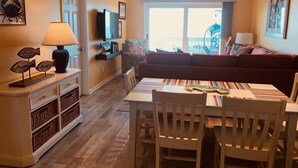 Een gezellige woonkamer met een bank, een eettafel met stoelen, een televisie en een plafondventilator.
