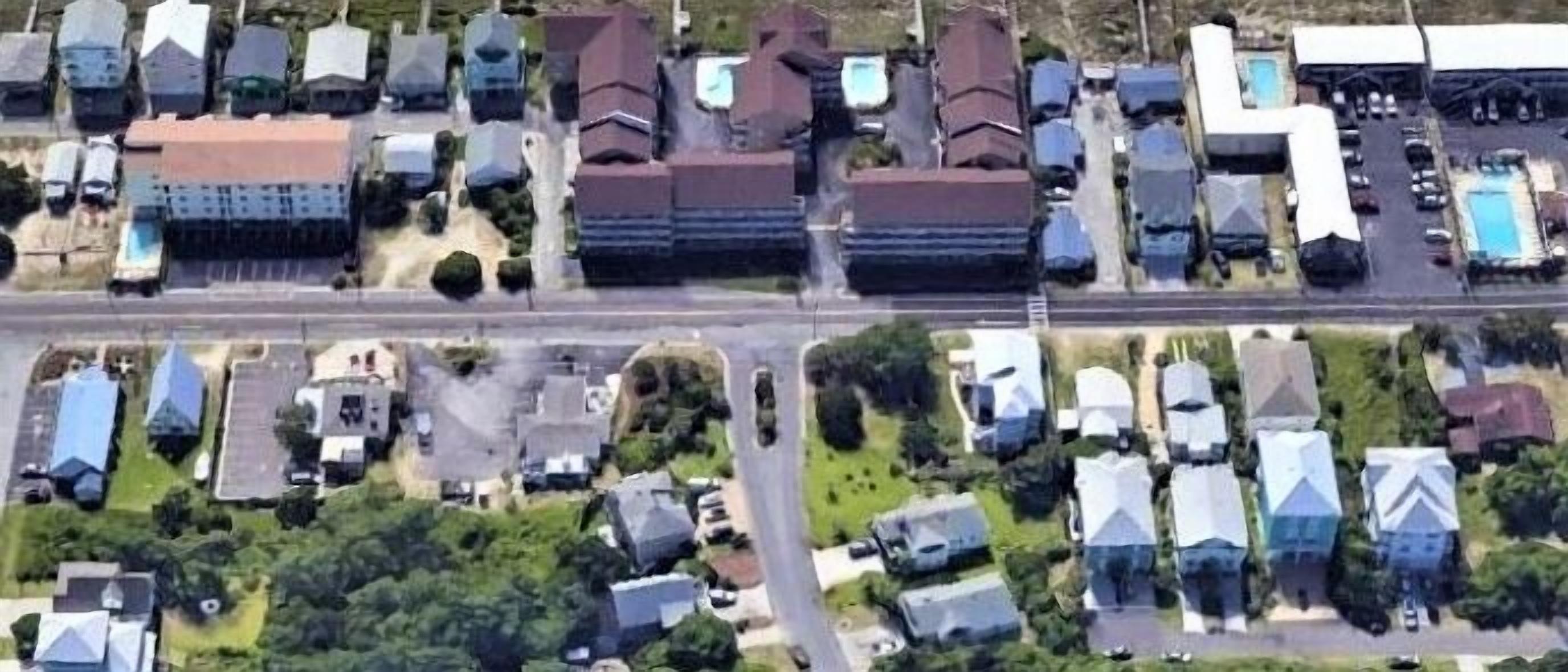 Luchtbeeld van een woonwijk met huizen, een weg en een zwembad.