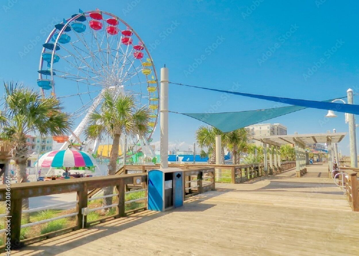 A boardwalk with a Ferris wheel and palm trees.