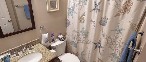 A bathroom with a double sink, toilet, and a shower curtain with a marine life pattern.