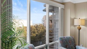 A room with a large window, a chair with a floral pattern, and a floor lamp. - OCEANFRONT!  Partial Ocean VIEW! Guaranteed CLEAN!! Villamare - Palmetto Dunes (Hilton Head)