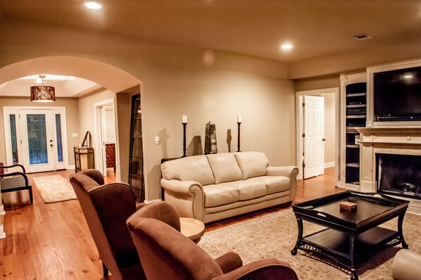 A living room with a beige sofa, a black coffee table, and a fireplace. - Southern Calm on a Deep Water Dock! (Mt Pleasant)