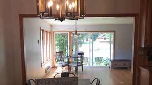 A dining area with a wooden table and chairs, a chandelier, and a sign that reads "BE OUR Guest".
