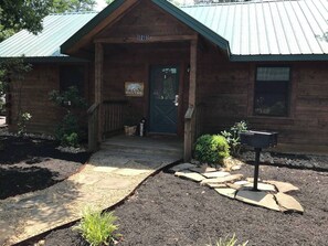 A wooden cabin with a green door, a welcome sign, and a mailbox.