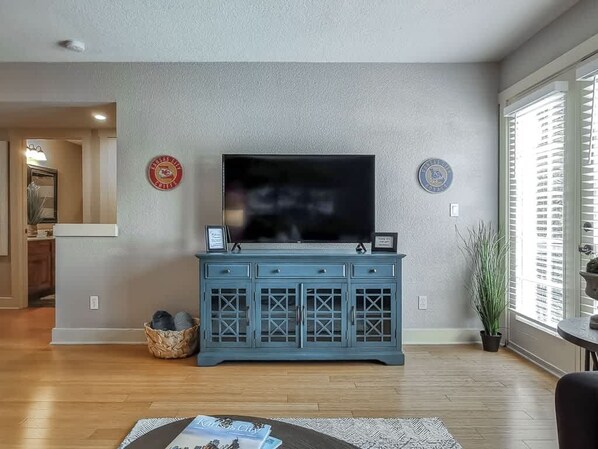 A living room with a flat-screen TV, a blue cabinet, and a potted plant.