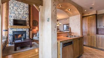 A modern kitchen with a stone fireplace, wooden cabinets, and a dishwasher.