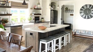 Una cocina moderna con una isla central, mesa de comedor de madera y taburetes de bar.