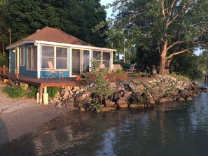 A house with a covered porch, a chair, and a table. - Drifted Inn - Riverfront Cabin (Amherstburg)