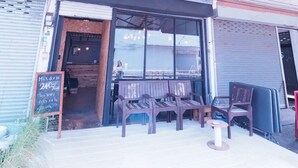 A café with outdoor seating, a sign offering a 24% discount, and a chalkboard menu. - Asleep Hostel (Kanchanaburi)
