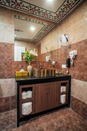 A bathroom with a wooden vanity, a mirror, a hairdryer, and a towel rack.