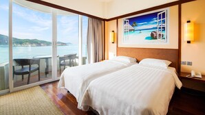 A hotel room with two beds, a balcony with a view of the sea, and a painting of a tropical scene. - The Warwick (Cheung Chau)