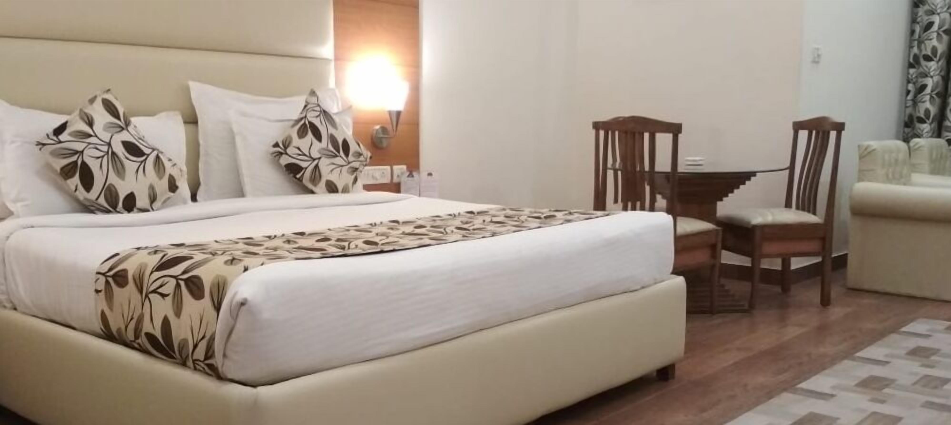 Une chambre d’hôtel avec un grand lit, un bureau avec deux chaises, un canapé et une table de chevet avec une lampe.