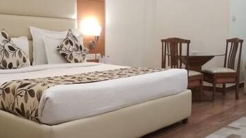 Une chambre d’hôtel avec un grand lit, un bureau avec deux chaises, un canapé et une table de chevet avec une lampe.