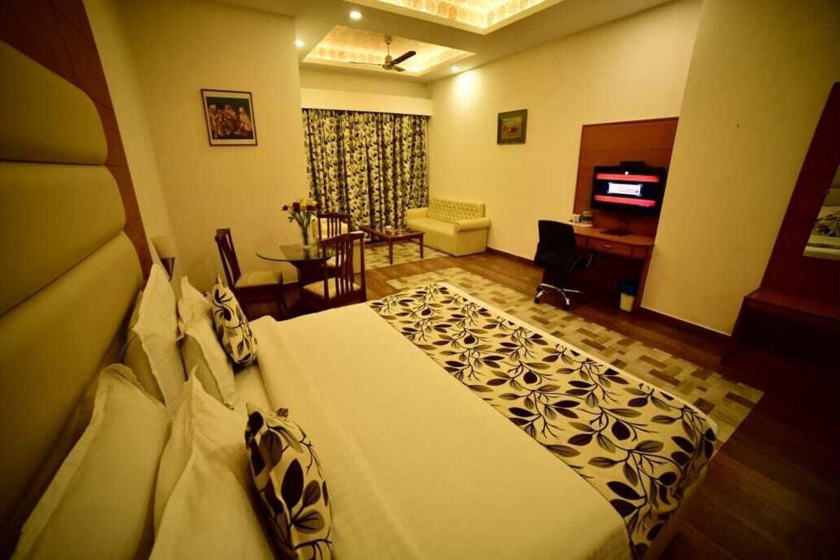 Una habitación de hotel con una cama grande, un escritorio, una silla, un sofá y un televisor.