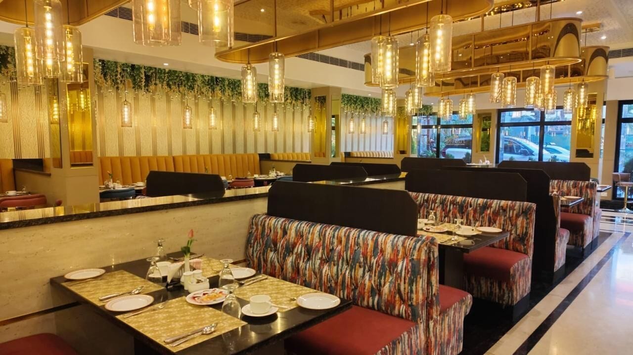 A restaurant with booths and tables, some with floral patterns, and hanging pendant lights.
