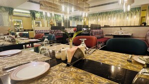 A restaurant with tables set for dining, featuring patterned tablecloths and elegant table settings. - Grand Continental Hotel  (Prayagraj)