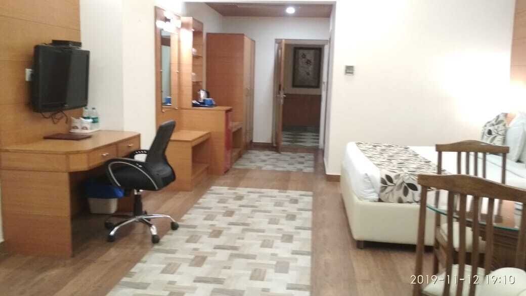 Een kleine hotelkamer met een bureau, stoel, bank en een televisie.
