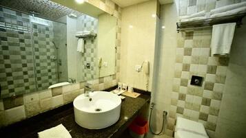 A bathroom with a round sink, a glass-enclosed shower, and a toilet.
