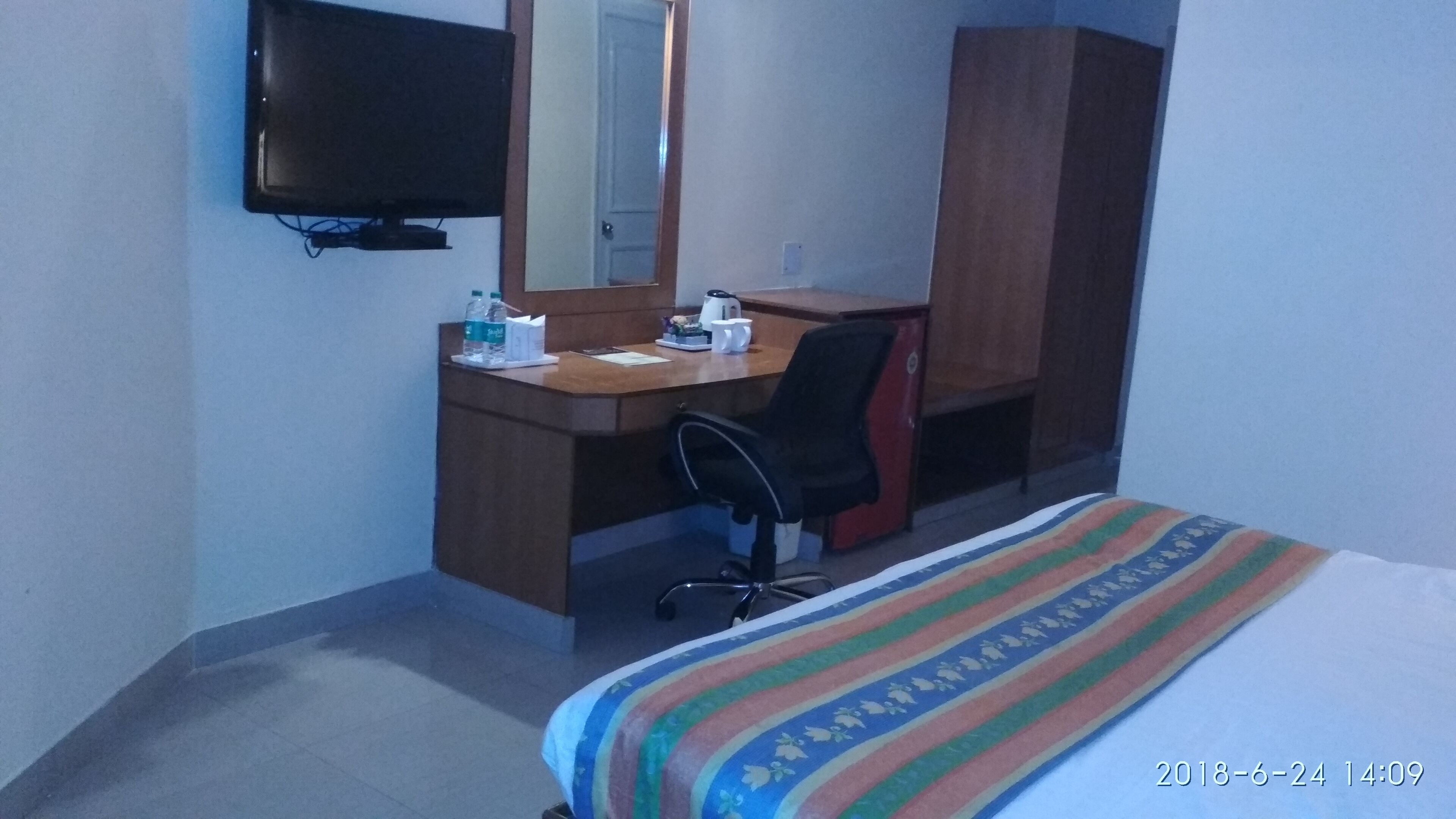 A hotel room with a bed, a desk, a chair, a television, and a wardrobe.