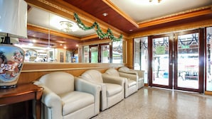 A lobby with a row of beige leather sofas, a wooden reception desk, and a large mirror reflecting the interior. - Thai Garden Resort (Bangkok)