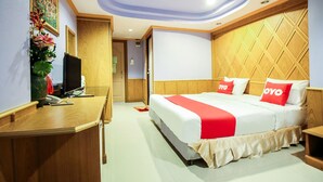 A hotel room with a bed, a desk, a television, and a decorative plant. - Thai Garden Resort (Bangkok)