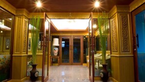 A hotel lobby with a central glass door, flanked by decorative panels and potted plants. - Thai Garden Resort (Bangkok)