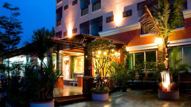 A hotel with a covered outdoor area featuring seating and potted plants. - Thai Garden Resort (Bangkok)