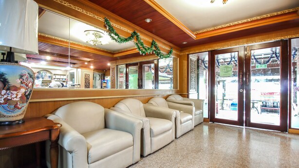 A lobby with a row of beige leather sofas, a wooden reception desk, and a large mirror reflecting the interior. - Thai Garden Resort (Bangkok)