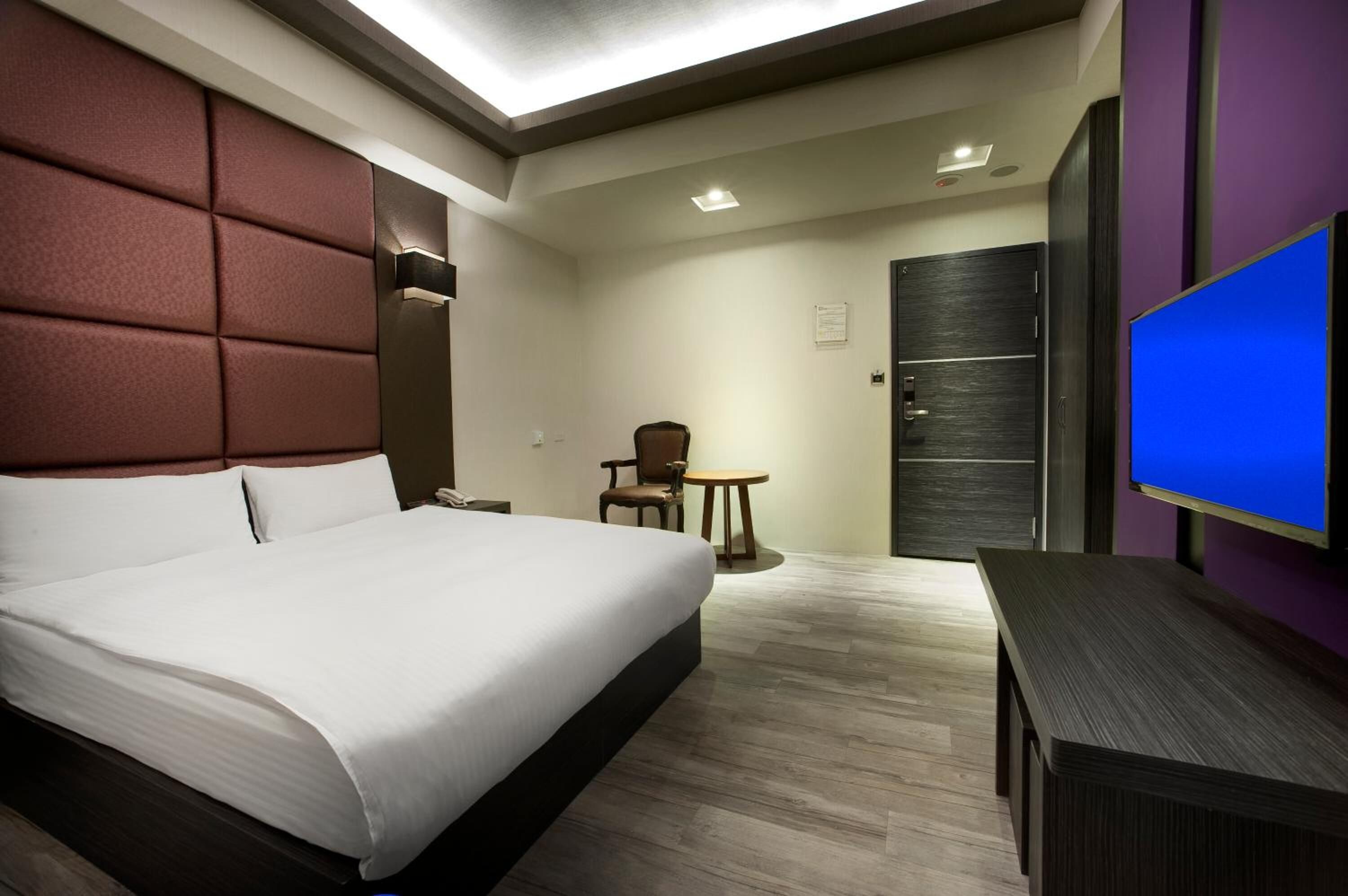 Een hotelkamer met een groot bed, een bureau, een stoel en een televisie.