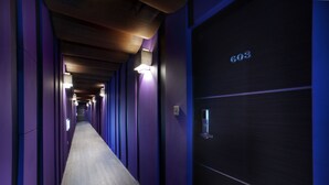 Un pasillo con paredes moradas, piso de madera y una puerta con la etiqueta '603'.