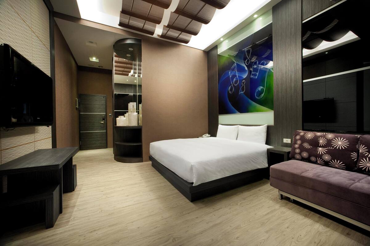 A modern bedroom with a bed, a sofa, a TV, and a built-in wardrobe.