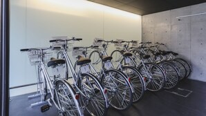 Estación de alquiler de bicicletas con varias bicicletas estacionadas en un espacio interior con paredes de concreto y piso.
