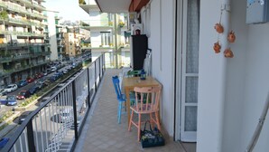 A balcony with a table, chairs, and a bag.