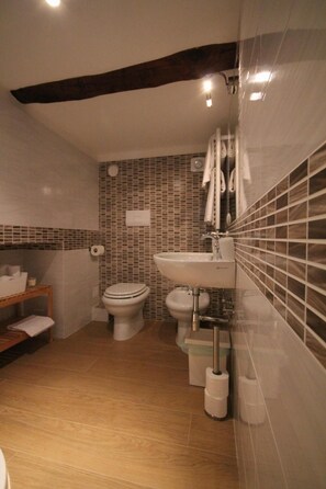 Ein Badezimmer mit Toilette, Bidet, Waschbecken und einem Holzboden mit Handtüchern.