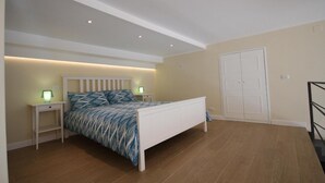A bedroom with a bed, nightstands, a wardrobe, and a staircase.