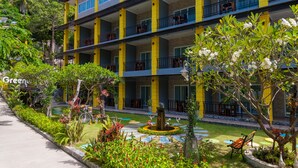 A multi-story hotel with balconies, a garden area with a fountain, and a sign that reads "Green". - Greenery Resort Koh Tao (Koh Tao)