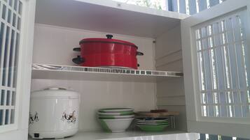 Una cocina con armarios blancos, una olla roja en la repisa superior y un electrodoméstico blanco con diseños de dibujos animados en la repisa inferior.