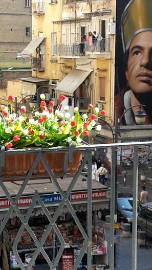 A street view with a flower display, a building with balconies, and a shop with various items. - Suite Duomo B&B & Apartment (Naples)