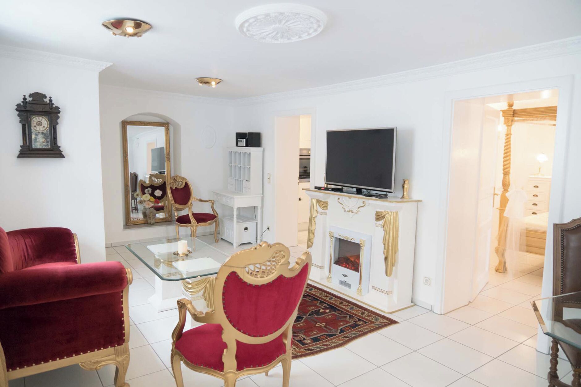 A spacious living room with a fireplace, a television, and a red velvet chair.