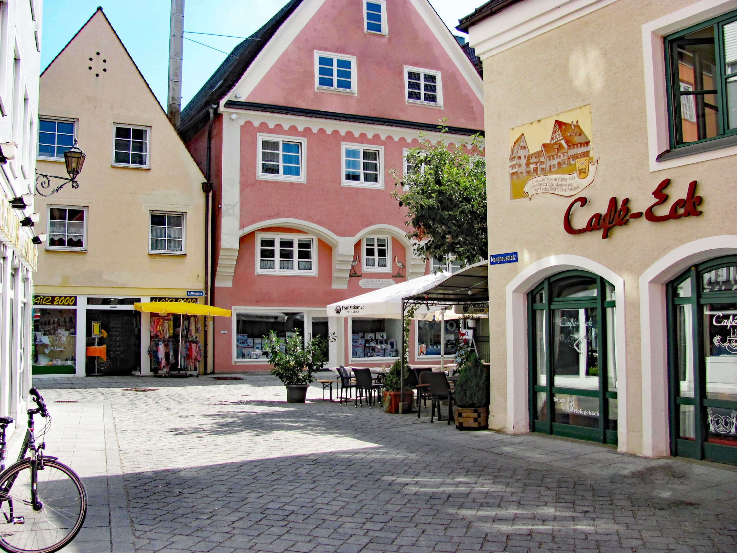A cobblestone street with buildings, a bicycle, and outdoor seating.
