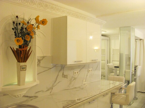 A modern bathroom with a marble countertop, a white cabinet, and a glass shower enclosure.