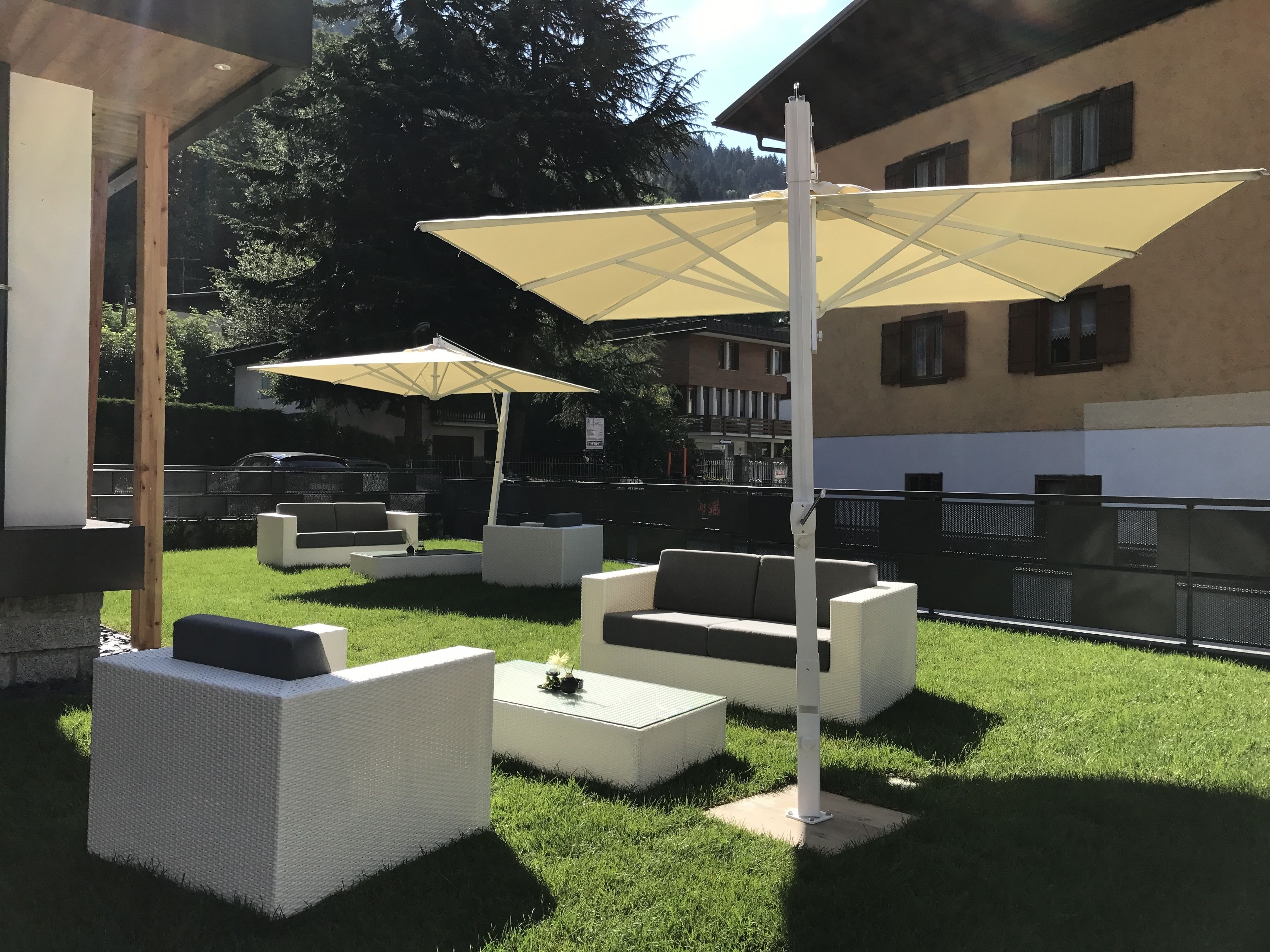 Un espace extérieur aménagé avec des meubles en osier blanc et de grands parasols.