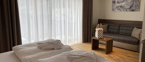 Una habitación de hotel con cama, sofá, una mesita y un cuadro en la pared.