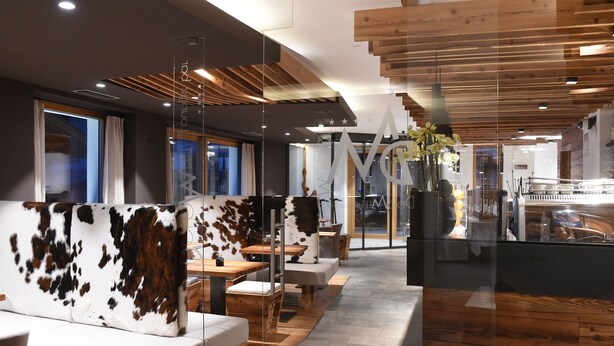 A restaurant with wooden ceiling panels, glass partitions, and a modern interior design. - Dolomeet Boutique Hotel (Pinzolo)