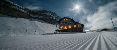 A snow-covered ski slope with a lodge in the background.