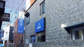 A building with a stone facade, a wooden upper floor, and signage for 'QuestHouse' and 'Bureta'. - Busan Inn (Busan)