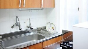 A kitchen with wooden cabinets, a stainless steel sink, and a stove. - Busan Inn (Busan)