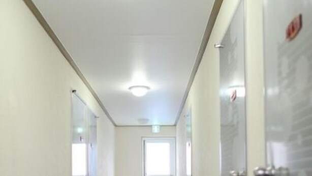 A modern hotel corridor with a central light fixture, glass doors, and a visible exit sign. - Busan Inn (Busan)